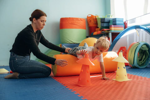 Enfant avec enseignant pendant exercices de motricité dans une salle de jeu